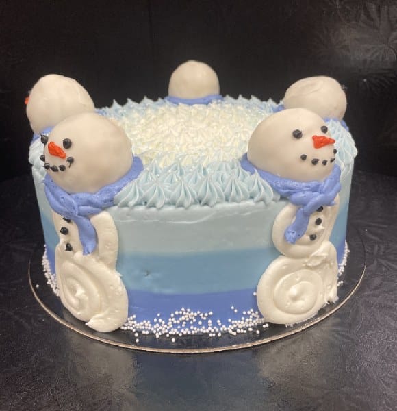 Round stacked cake in ombre blue colours with five snowmen on the sides.